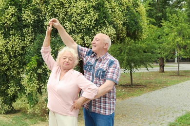 Cute elderly couple in love dancing outdoors