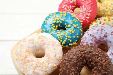 Photo of Yummy donuts with sprinkles on white wooden table, closeup