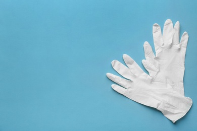 Pair of medical gloves on blue background, flat lay. Space for text