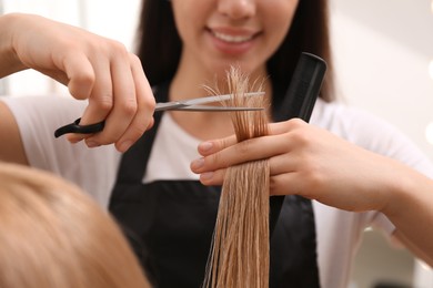 Stylist cutting hair of client in professional salon, closeup