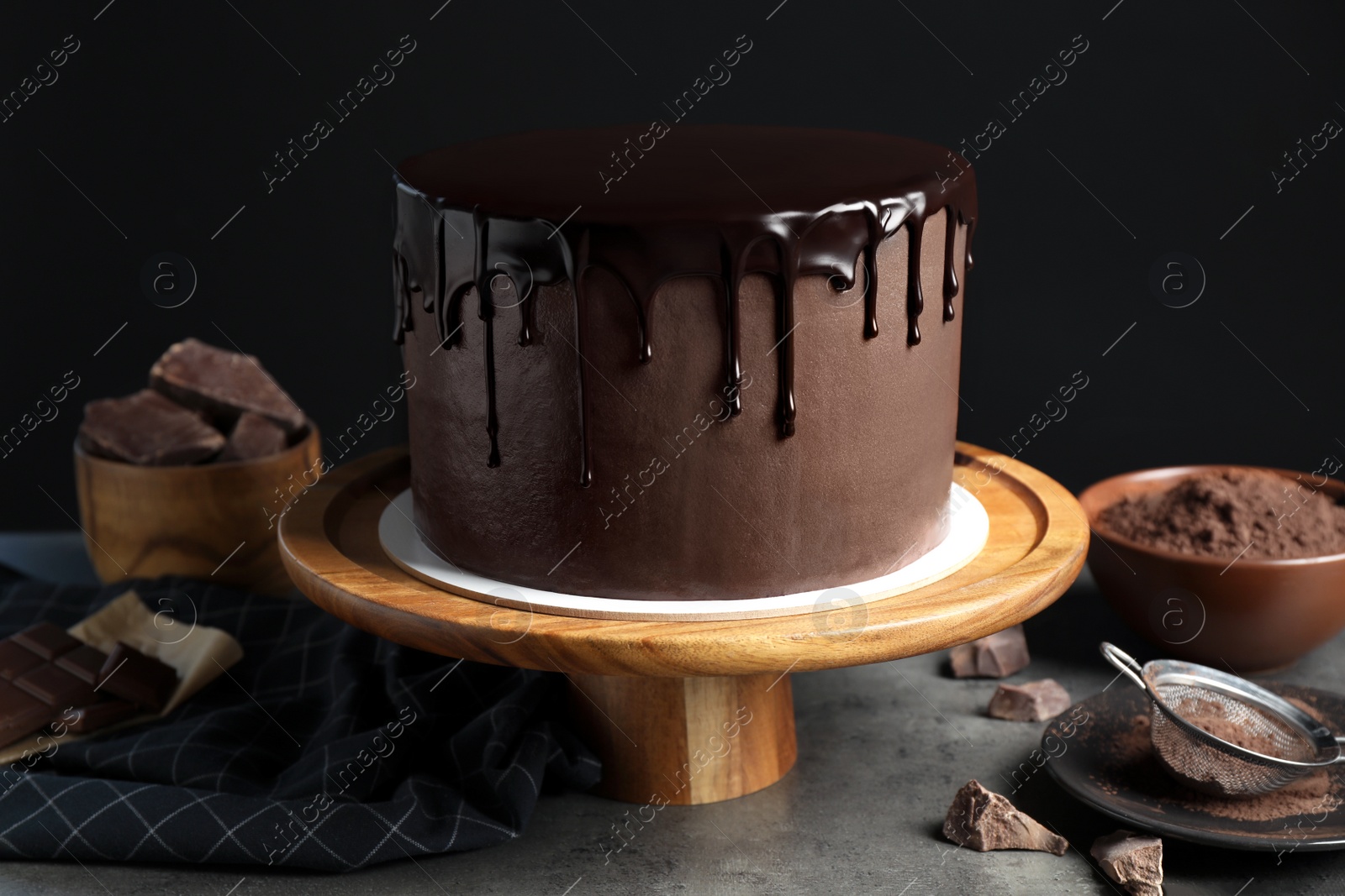 Photo of Freshly made delicious chocolate cake on grey table against black background