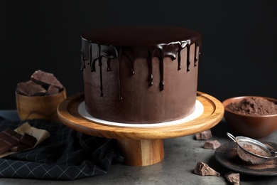 Photo of Freshly made delicious chocolate cake on grey table against black background