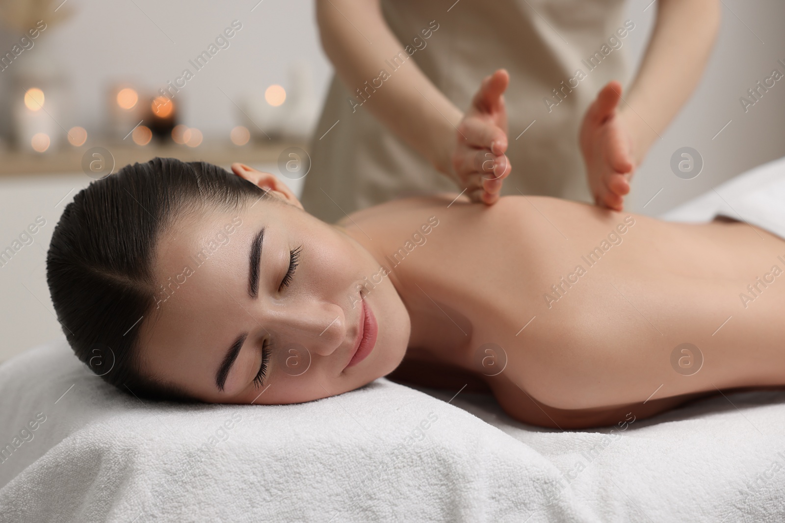 Photo of Woman receiving back massage on couch in spa salon