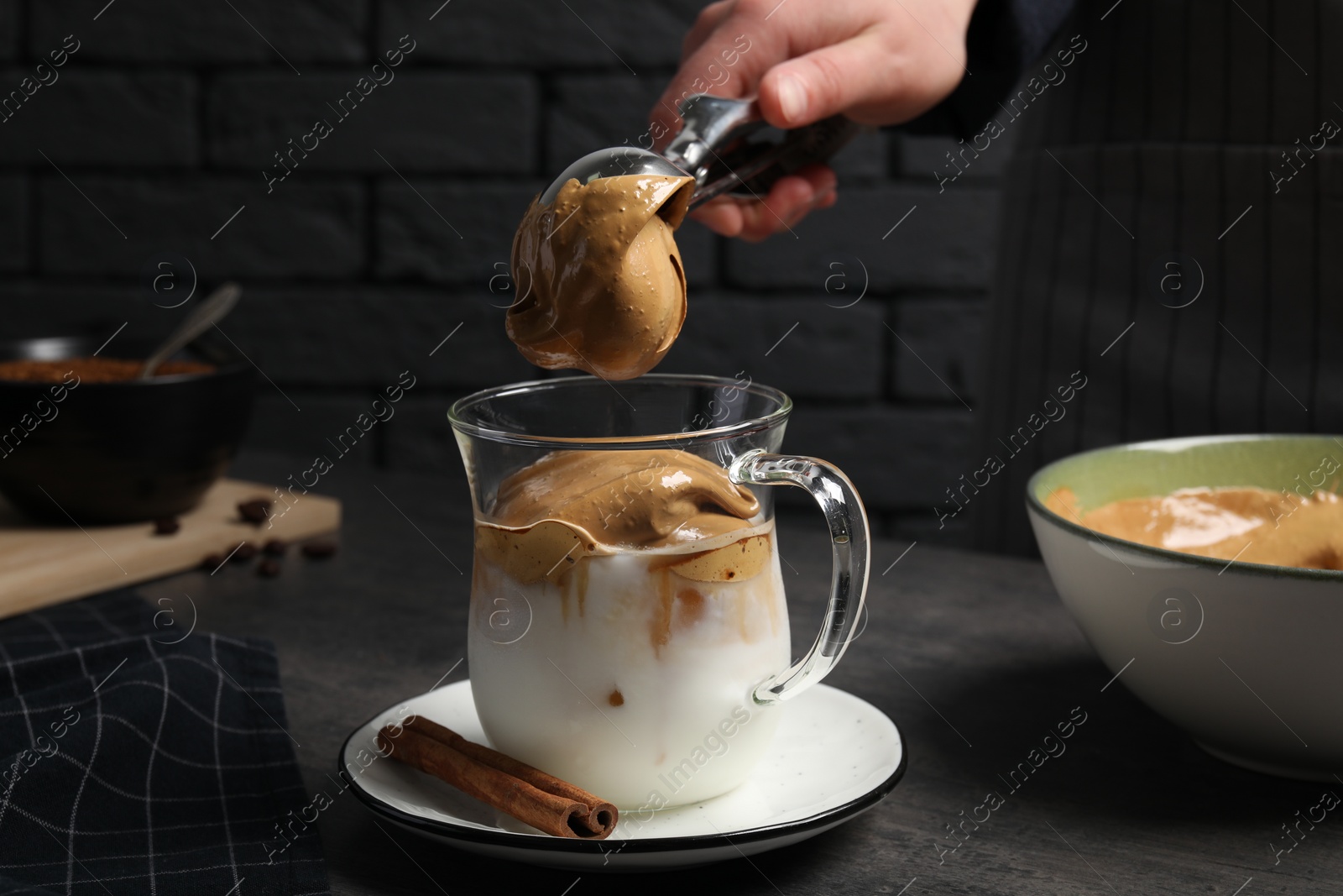 Photo of Woman making dalgona coffee at grey table, closeup