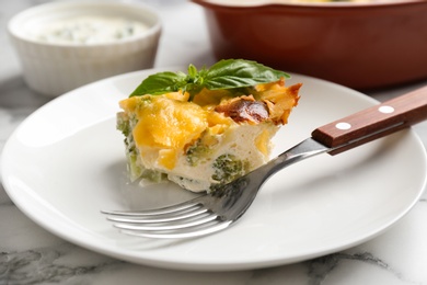 Photo of Piece of tasty broccoli casserole on white marble table