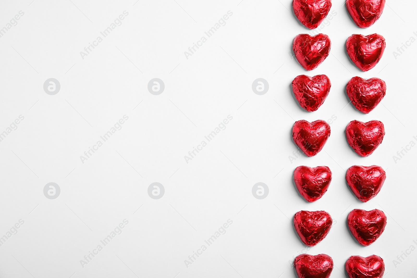 Photo of Heart shaped chocolate candies on white background, flat lay with space for text. Valentine's day treat