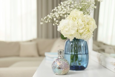 Photo of Stylish catalytic lamp with beautiful bouquet on white table in living room, space for text. Cozy interior