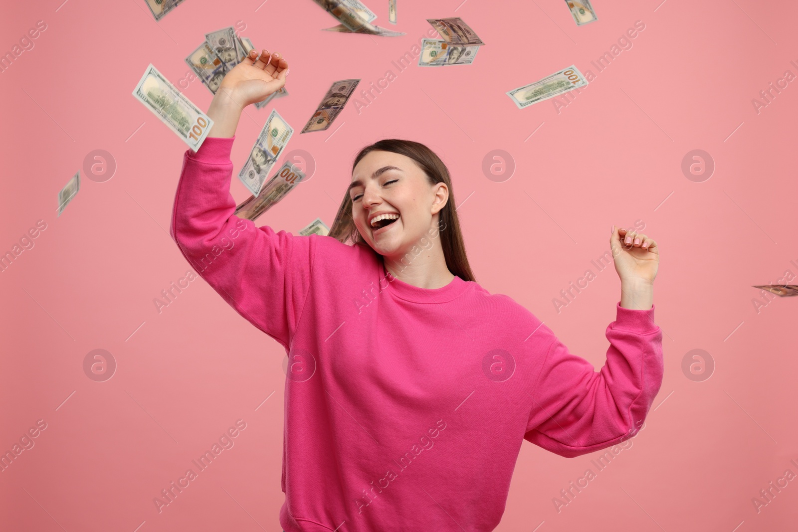 Photo of Happy woman under money shower on pink background