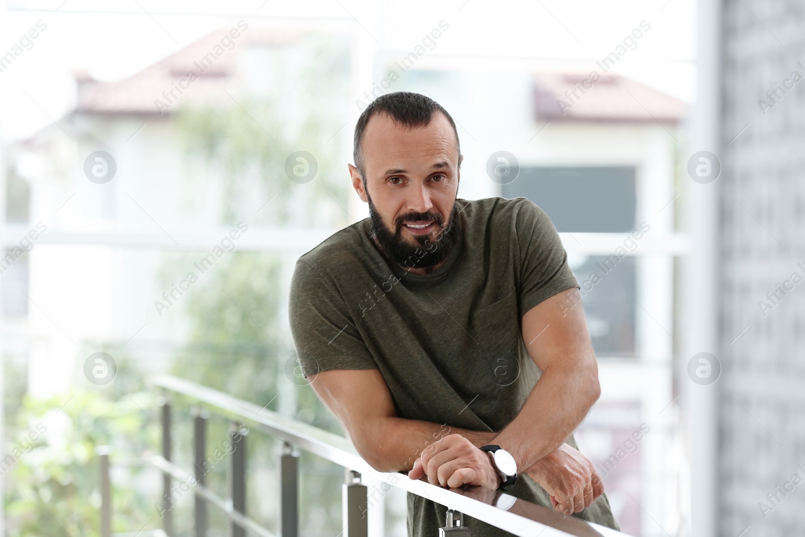 Photo of Portrait of handsome mature man leaning on handrail indoors