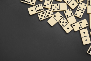 Photo of Classic domino tiles on black background, flat lay. Space for text