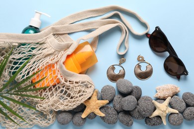 Photo of String bag and different beach accessories on light blue background, flat lay