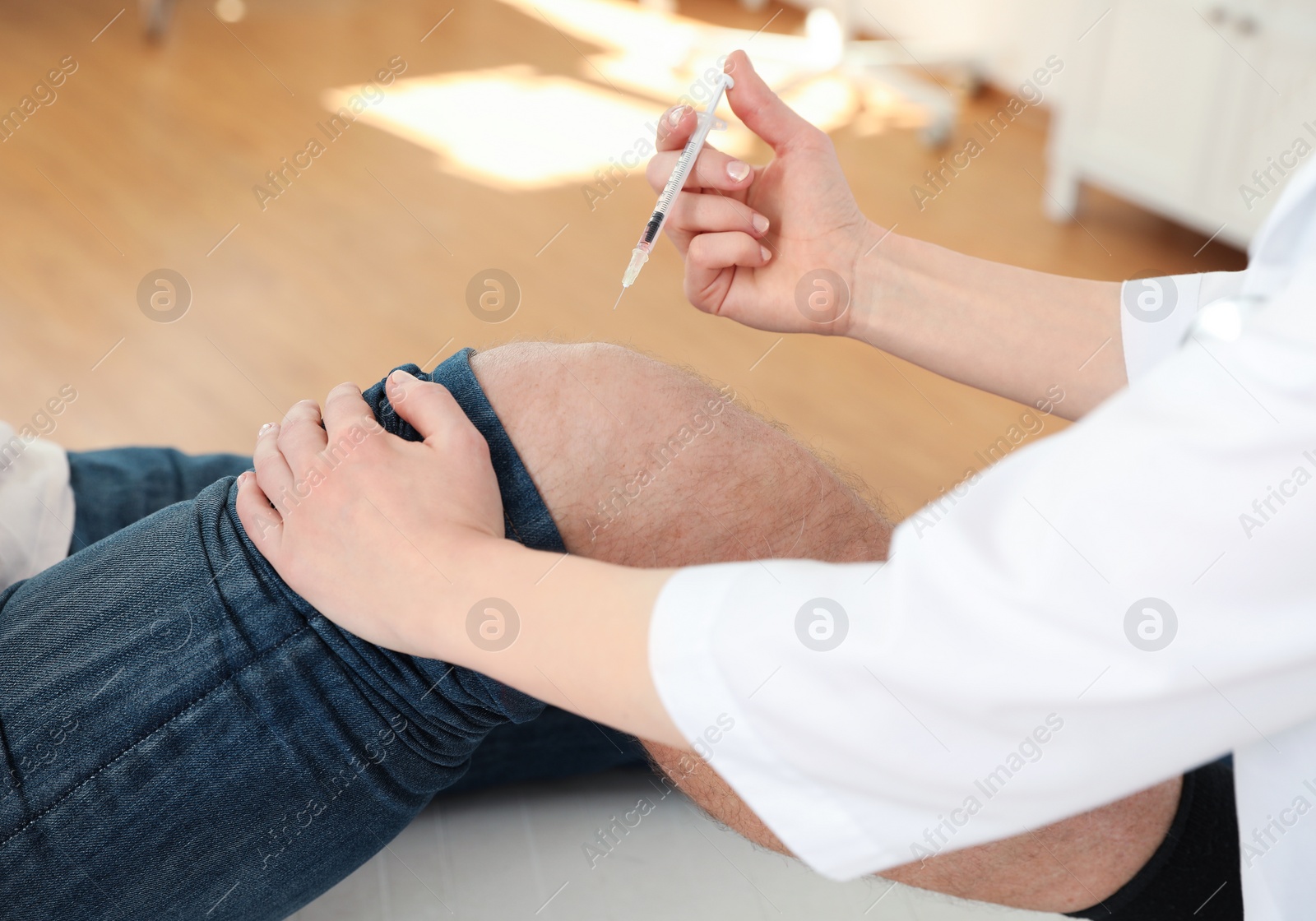 Photo of Doctor giving patient injection in clinic, closeup. Knee problem treatment