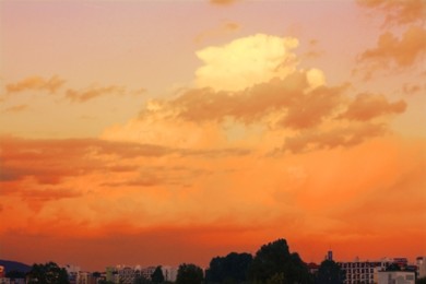 Image of Beautiful orange sky with clouds over city at sunset