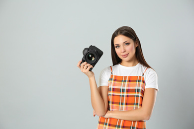 Photo of Professional photographer working on light grey background in studio. Space for text