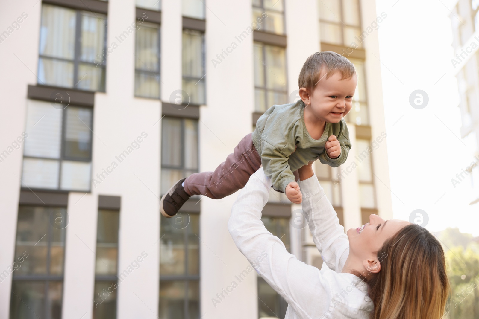 Photo of Happy nanny with cute little boy having fun outdoors, space for text