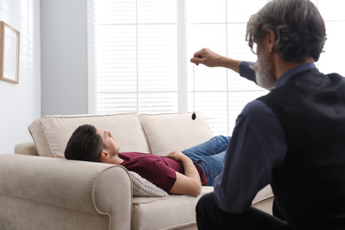 Photo of Psychotherapist using pendulum during hypnotherapy   session in office