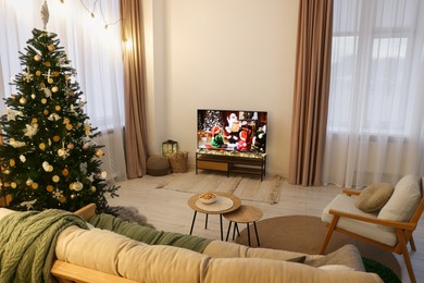 Wide TV set, furniture and Christmas tree in stylish room