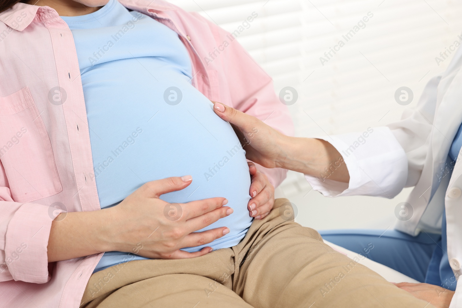 Photo of Pregnancy checkup. Doctor examining patient's tummy in clinic, closeup