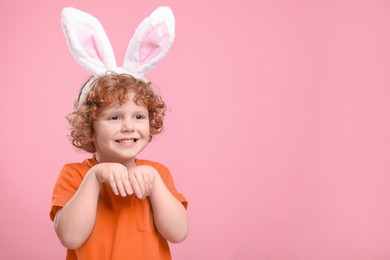 Happy boy wearing cute bunny ears headband on pink background, space for text. Easter celebration