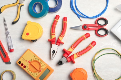 Photo of Set of electrician's tools on light background, flat lay