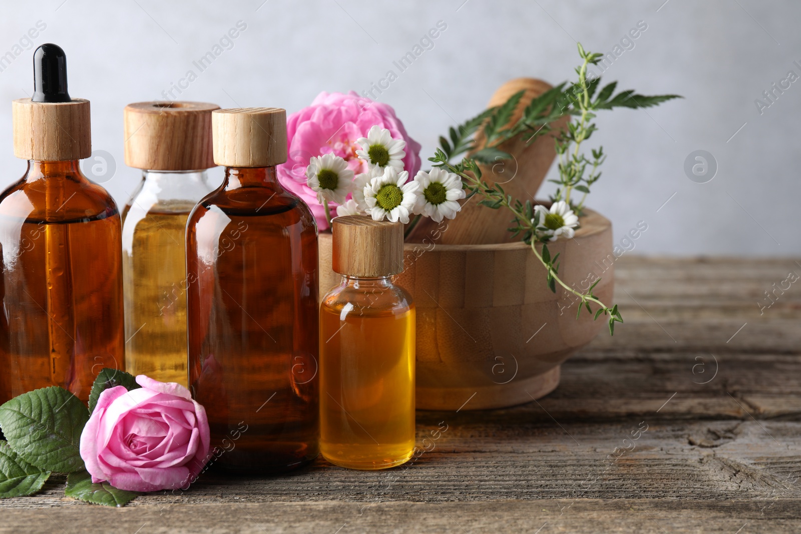 Photo of Aromatherapy. Different essential oils, flowers, mortar and pestle on wooden table