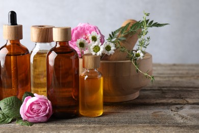 Photo of Aromatherapy. Different essential oils, flowers, mortar and pestle on wooden table