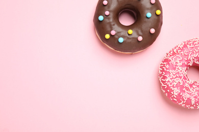 Delicious glazed donuts on pink background, flat lay. Space for text
