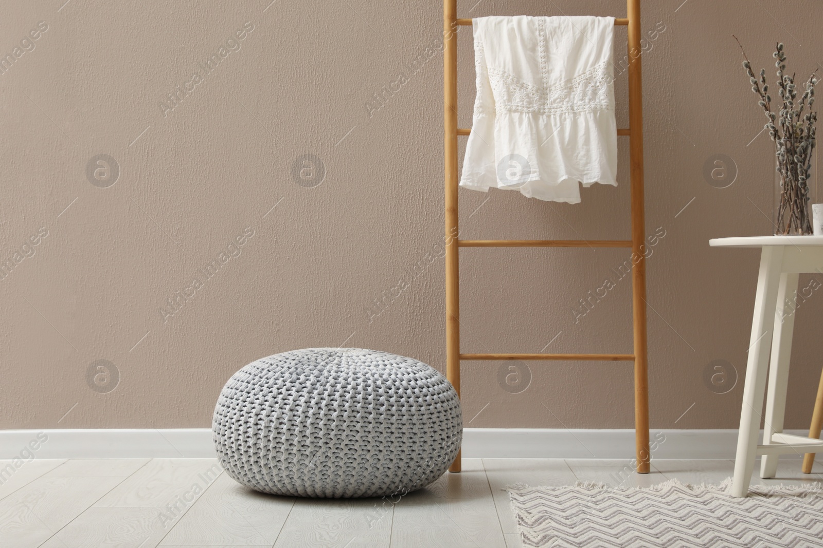 Photo of Stylish room interior with pouf, ladder and decor elements. Space for text