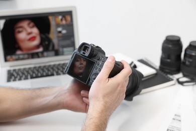 Professional photographer with digital camera at table indoors, closeup