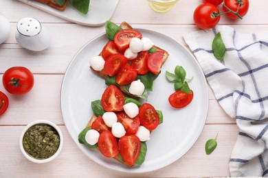 Photo of Delicious Caprese sandwiches with mozzarella, tomatoes, basil and pesto sauce on white wooden table, flat lay