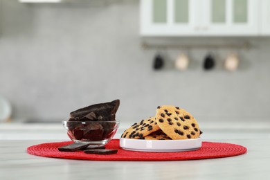 Photo of Delicious chocolate and tasty cookies on white marble table in kitchen