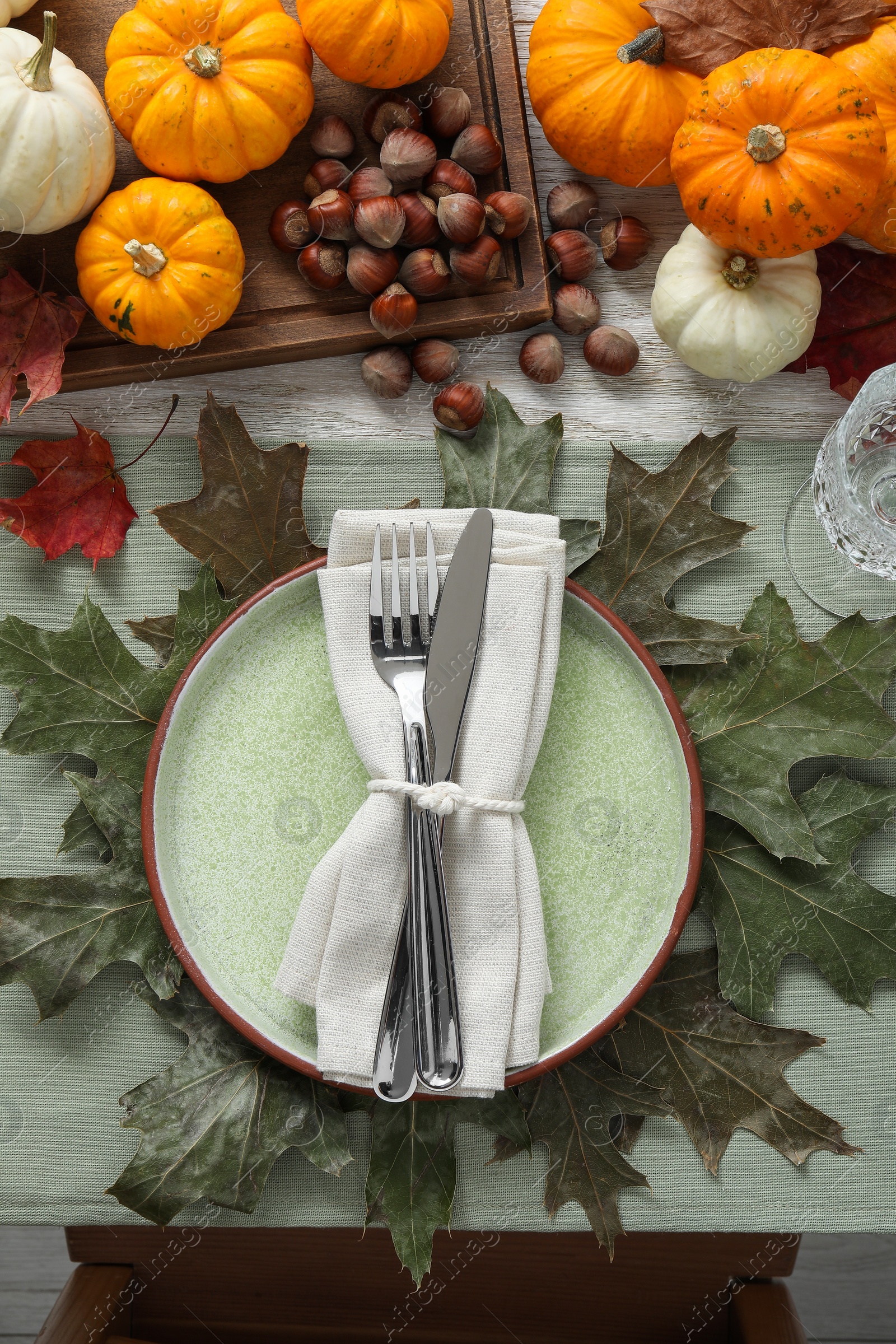 Photo of Happy Thanksgiving day. Beautiful table setting with autumn leaves, hazelnuts and pumpkins, flat lay