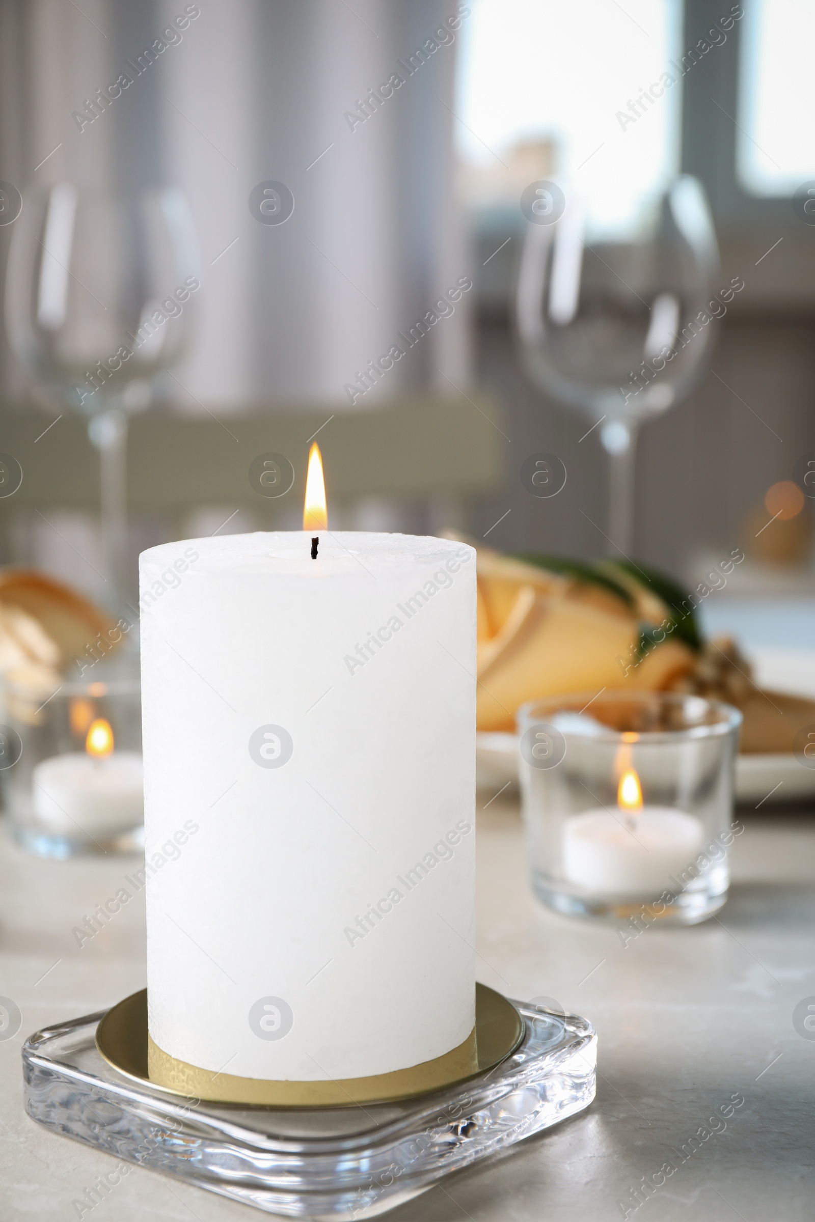 Photo of White burning wax candle on light table