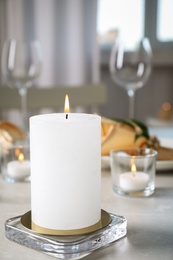 Photo of White burning wax candle on light table