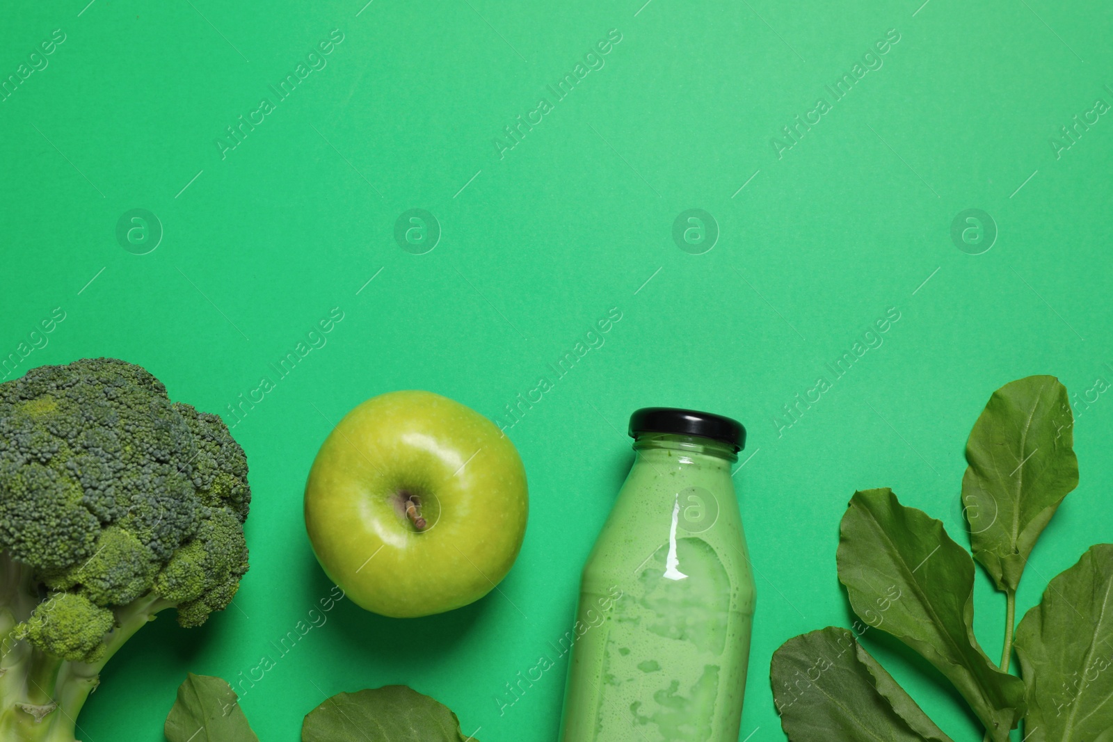 Photo of Bottle of delicious smoothie and ingredients on green background, flat lay. Space for text