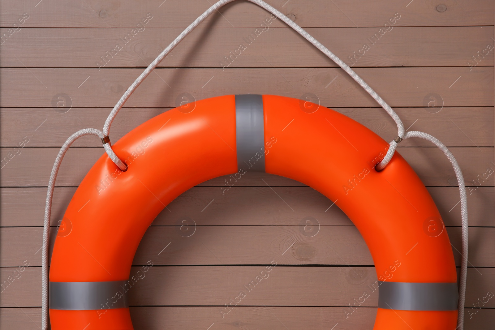 Photo of Orange lifebuoy on light brown wooden background. Rescue equipment