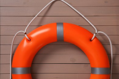 Photo of Orange lifebuoy on light brown wooden background. Rescue equipment