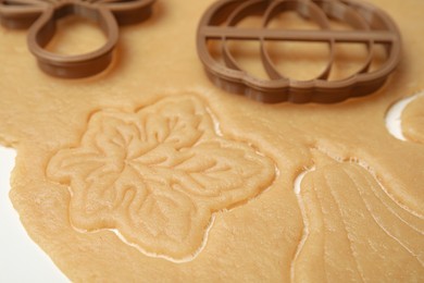 Photo of Cookie cutters and dough on white table, closeup