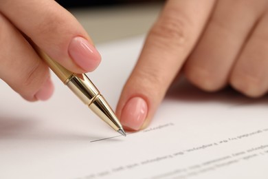 Woman signing document with pen, closeup view