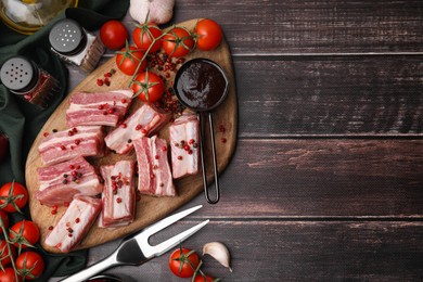 Photo of Flat lay composition with cut raw pork ribs and sauce on wooden table. Space for text