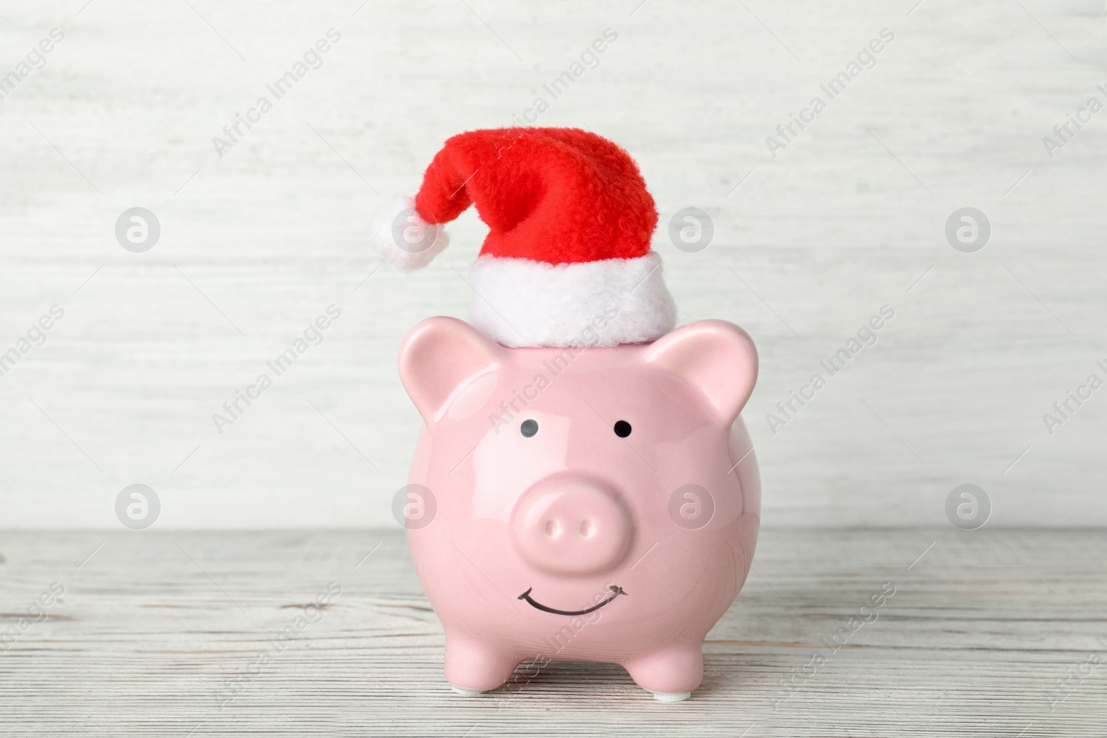 Photo of Cute piggy bank with Santa hat on table