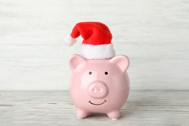 Photo of Cute piggy bank with Santa hat on table