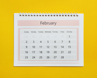 Photo of February calendar on yellow background, top view
