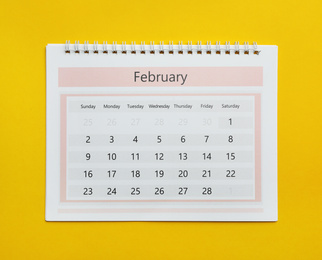 February calendar on yellow background, top view