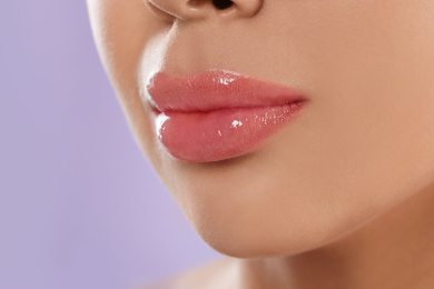 Photo of Young woman with beautiful full lips on lilac background, closeup