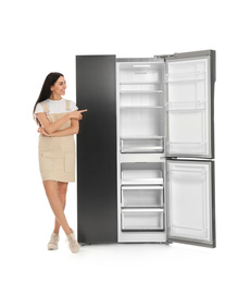 Photo of Young woman near empty refrigerator on white background
