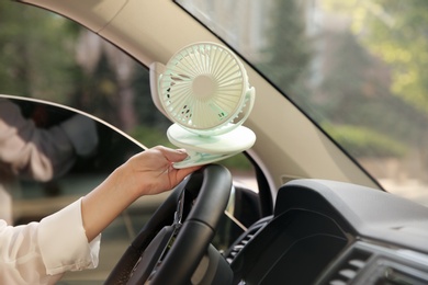 Photo of Woman with portable fan in car on hot summer day, closeup