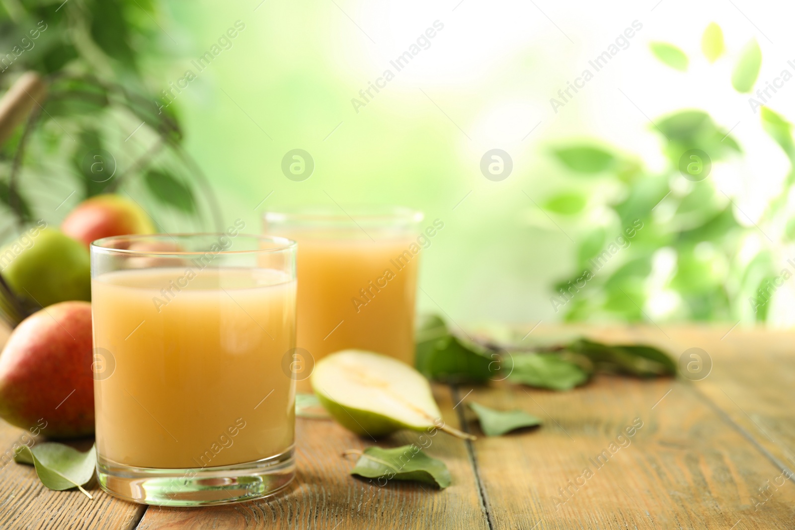 Photo of Fresh pear juice in glass on wooden table, closeup. Space for text