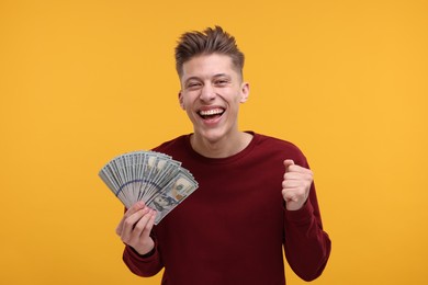 Photo of Happy man with dollar banknotes on yellow background