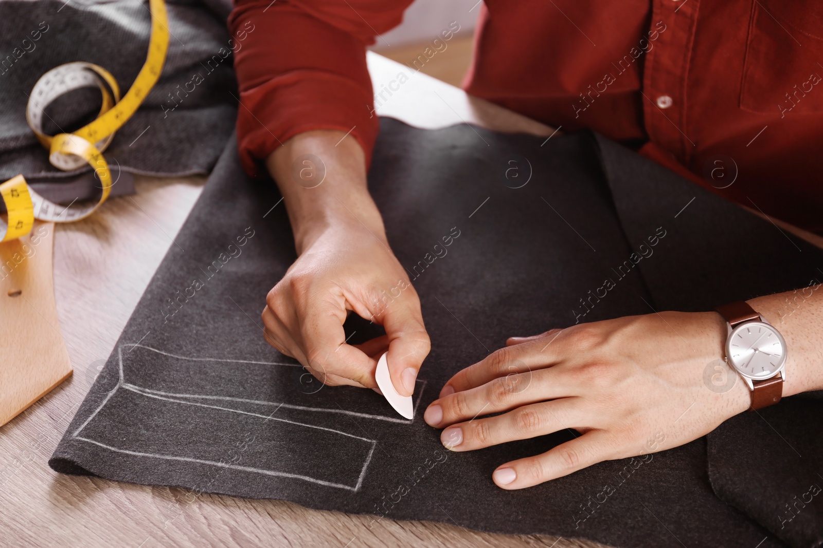 Photo of Tailor working with cloth at table in atelier